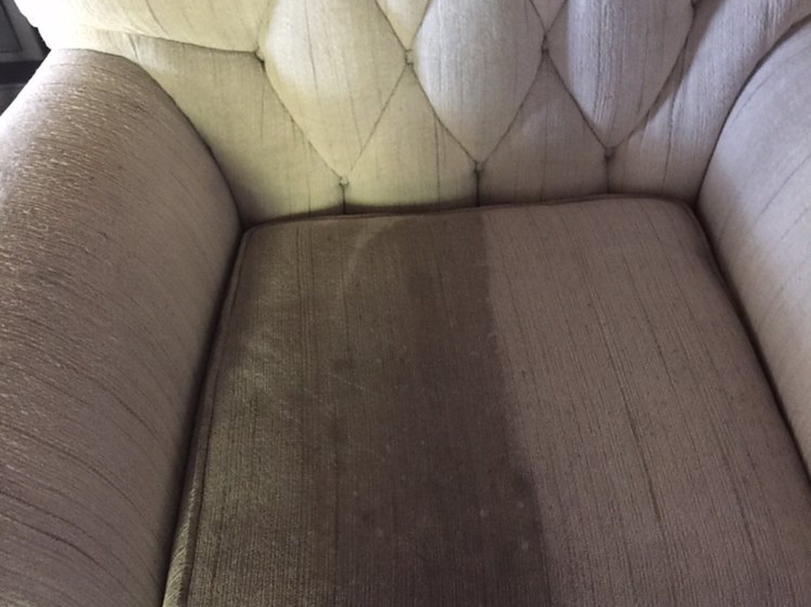 A tufted armchair seat cushion with the cleaned half beside the untouched half
