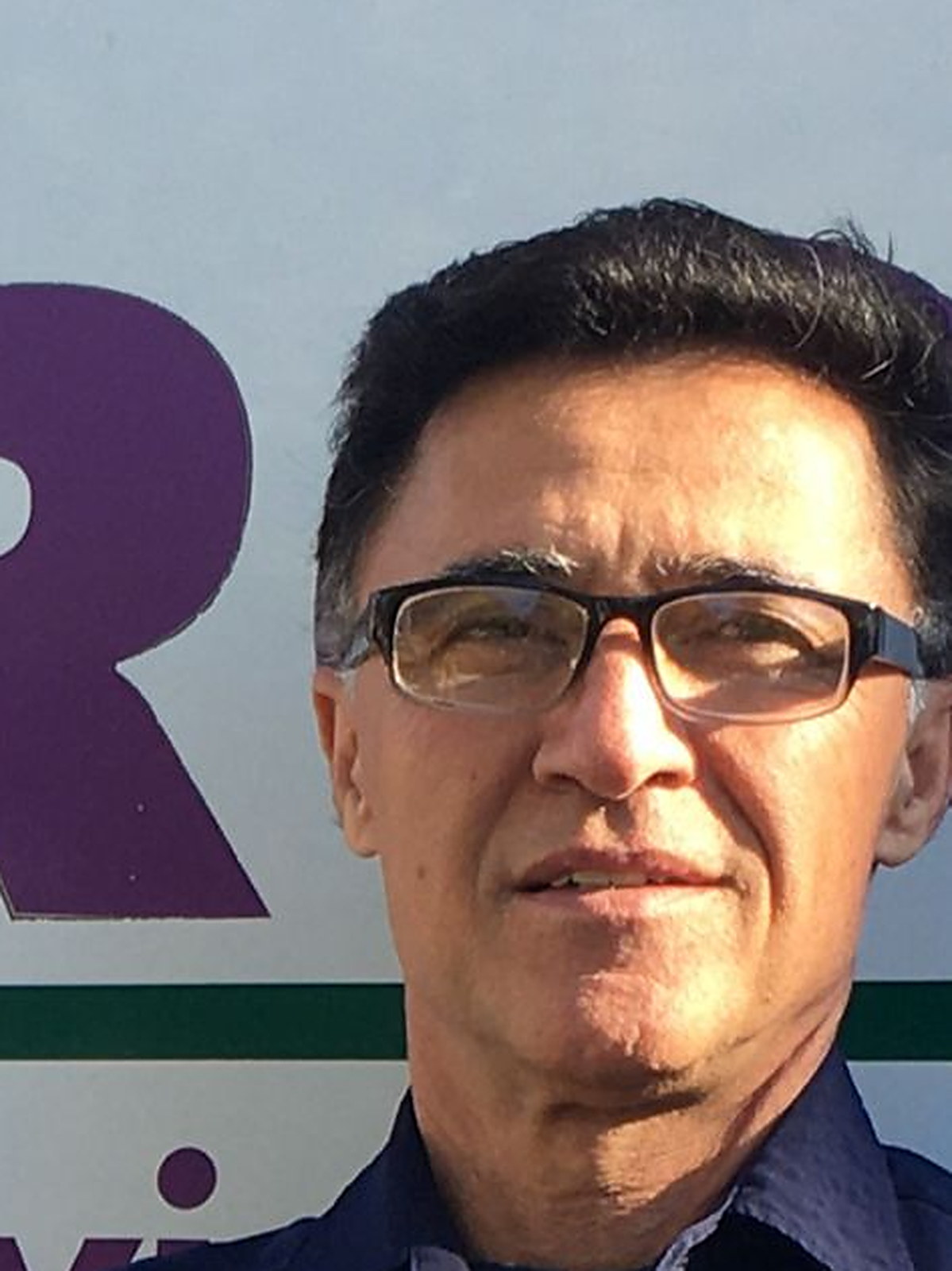 Masood Amirkhani in front of his van, the purple lettering and the green stripe of the livery behind him